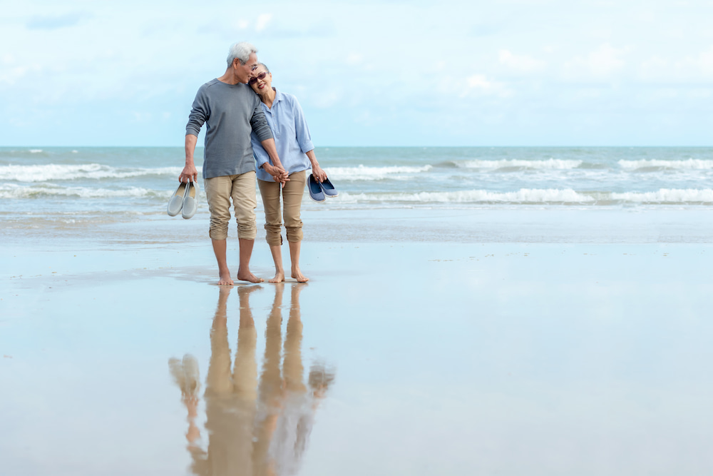 Older couple walking on the beach in the daytime