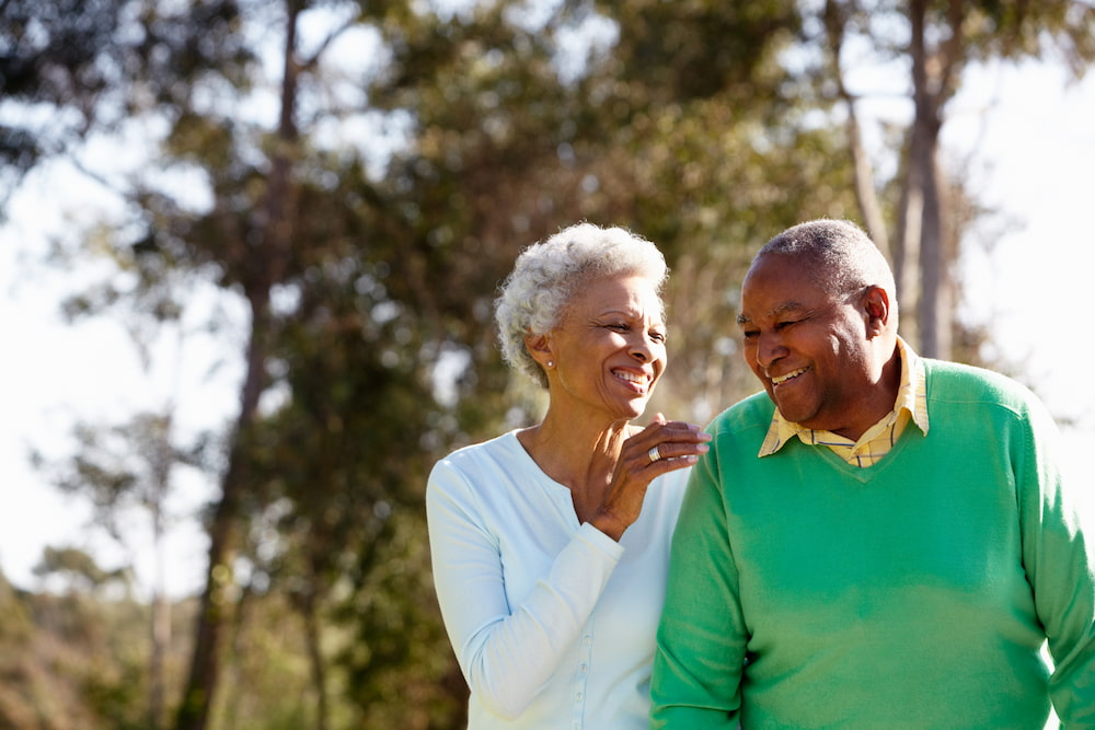 Older black couple walking in the park happily